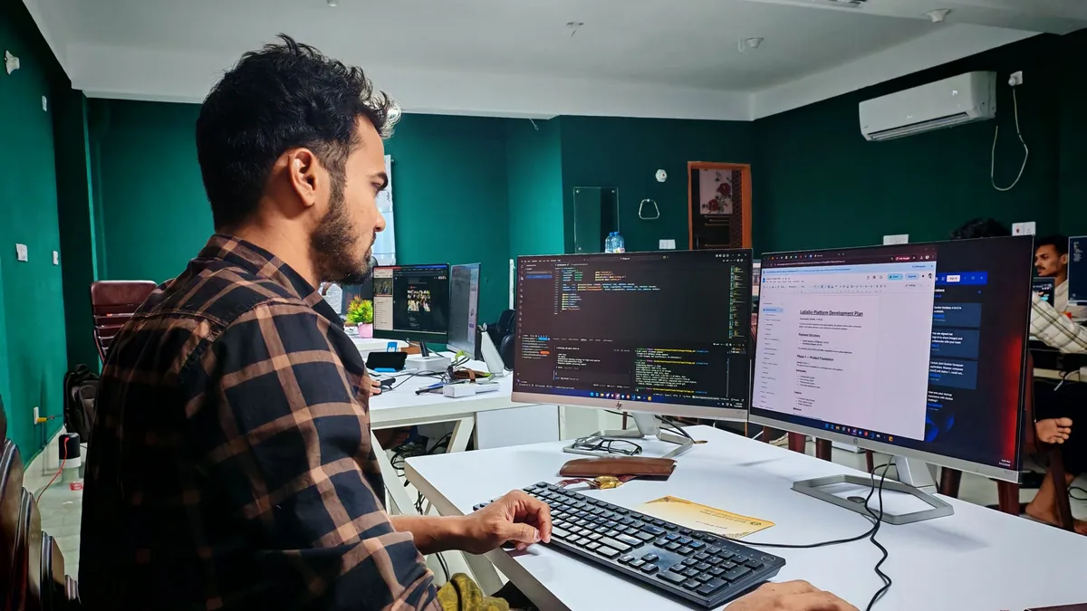 Sviluppatore che controlla codice e sistemi su due monitor